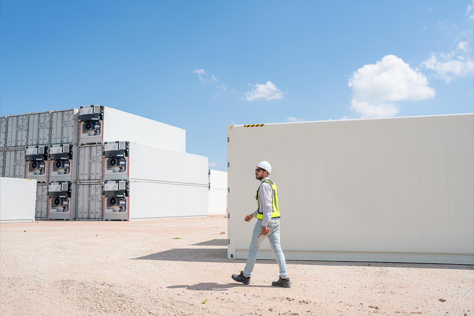 Power Solutions A worker walking outside power storage units at a construction site