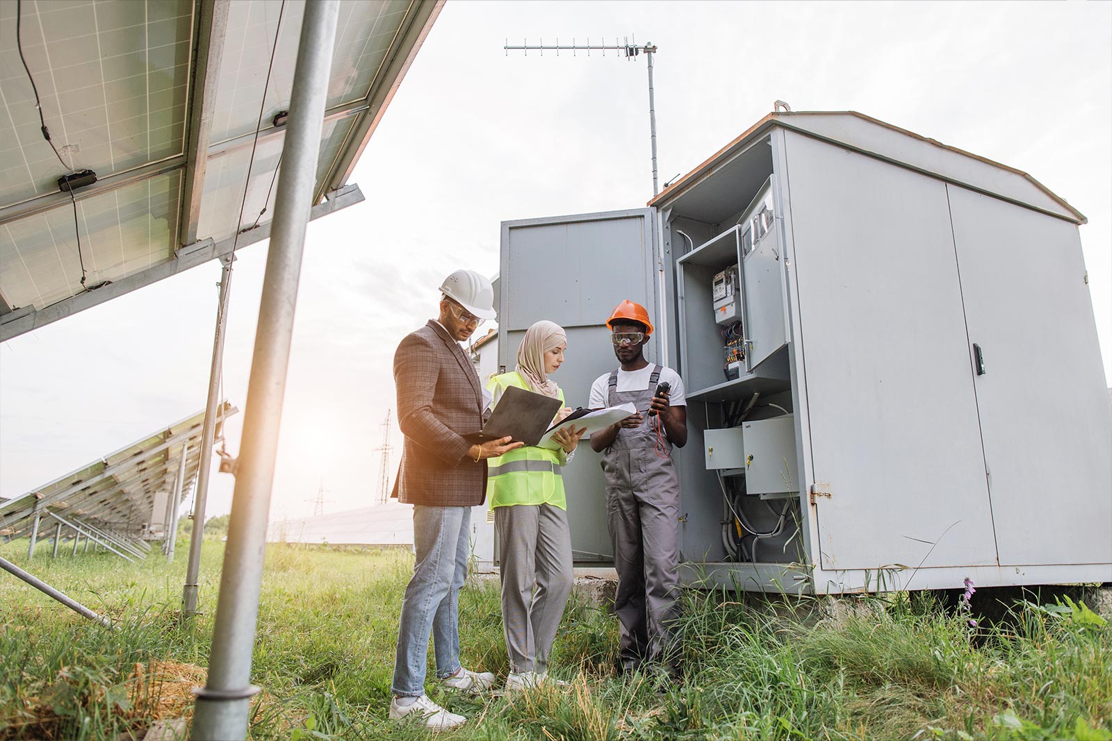 Power Solutions Three contractors stand outside solar panels and a linked power storage system